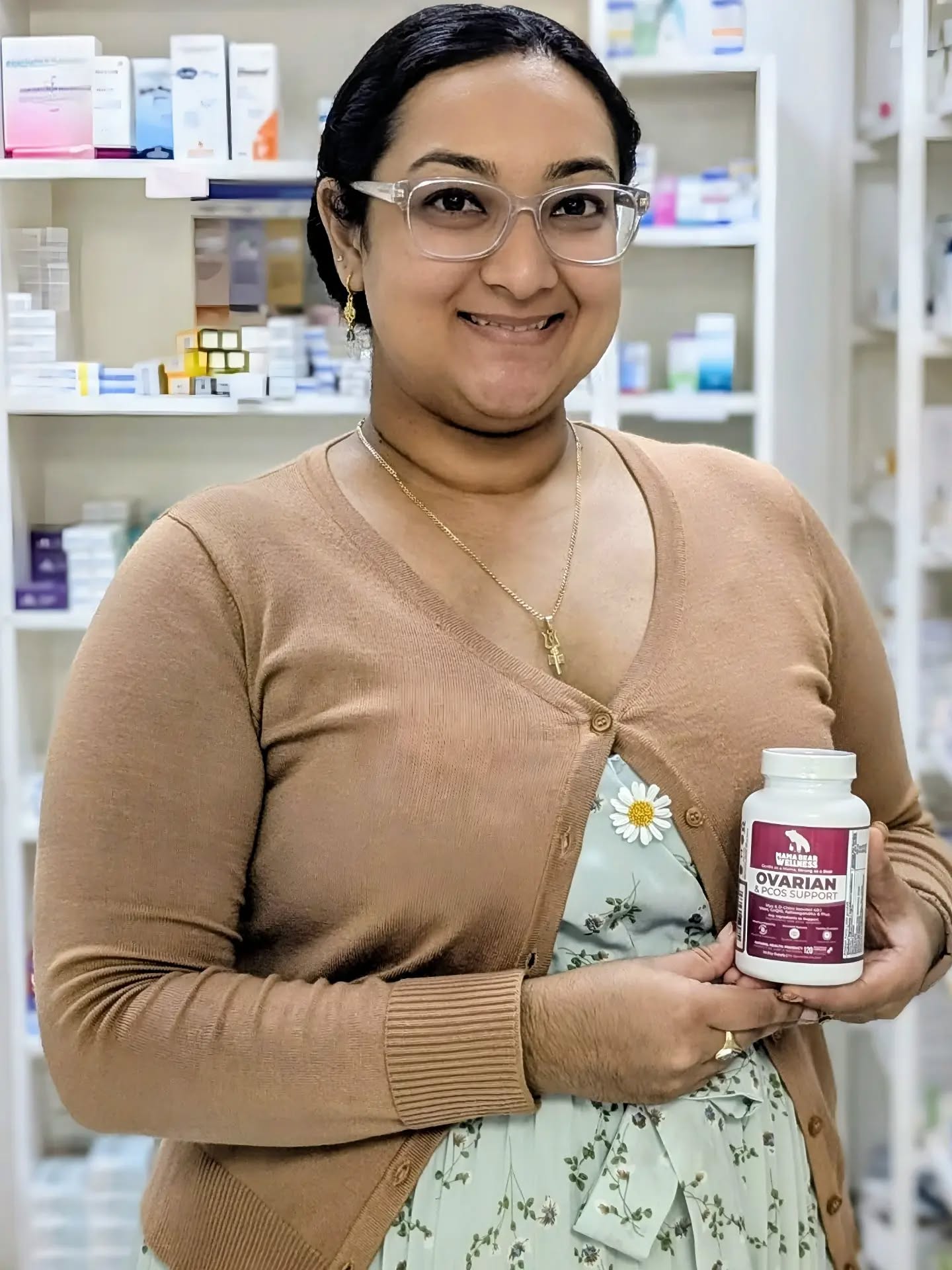 Customer smiling while holding her bottle of Mama Bear Ovarian & PCOS Support inside a Caribbean pharmacy in Barbados